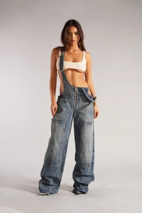 Détail de la salopette en jean délavé bleu foncé avec zip en métal et coupe jambe large