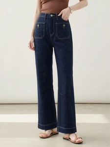 Dettaglio dei jeans a vita alta blu scuro con cuciture a contrasto bianche e bottoni dorati