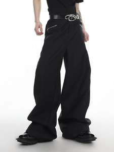 Detailansicht der schwarzen Herrenhose mit weitem Bein, Reißverschlusstaschen und Gürtel