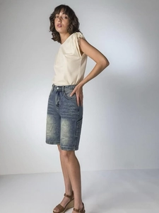 Détail d'un short en jean bleu avec poches cargo et haut en tricot blanc de profil