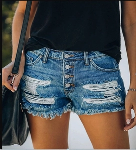 Close-up of distressed blue denim shorts featuring four metal buttons and frayed edges