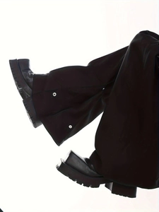 Detailansicht der schwarzen Hose mit weitem Bein und silbernen Druckknöpfen am Saum