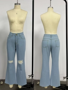 Dettaglio dei jeans a zampa a vita alta celeste con strappo sul ginocchio e bordo a taglio vivo