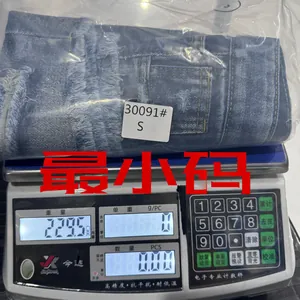 Détail d'un short en jean délavé bleu avec franges et trous usés sur une balance d'usine