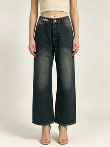 Detailed macro view of high-waist vintage dark blue denim jeans with metal button and woven label