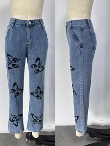 Détail d'un jean droit bleu clair avec imprimés papillons noirs et finition délavée