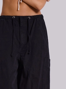 Dettaglio dei pantaloncini cargo neri con coulisse in vita e occhielli metallici
