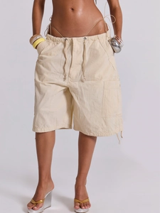 Dettaglio dei pantaloncini cargo beige con coulisse, vita elastica e grandi tasche laterali