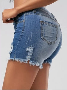 Detail view of high waist denim shorts featuring ripped holes and frayed raw hem design