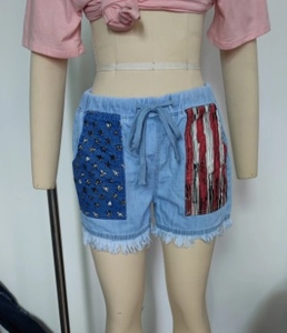 Detail der US-Flaggen-Taschen und Fransen an den hellblauen Denim-Shorts für Damen