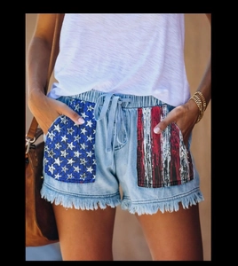 Detail der High-Waist-Denim-Shorts mit US-Flaggen-Taschen und Fransensaum
