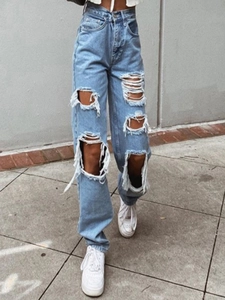 Macro shot of distressed knee details on light blue high-waisted wide-leg denim jeans