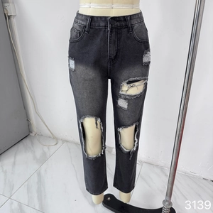 Detail shot of black distressed denim jeans with ripped knees and frayed edges