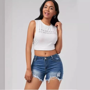 Distressed dark blue denim shorts with fringe and white crop top on model