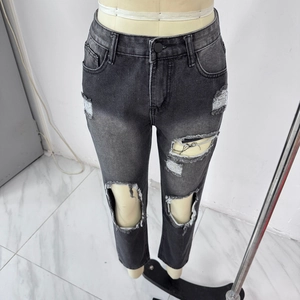 Detail shot of distressed dark grey high waisted ripped jeans with street style knee tears