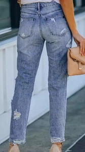 Close-up of the back pockets and distressed details on slim fit light blue ripped jeans