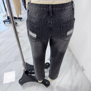 Macro shot of back pockets on high waist distressed slim gray denim jeans for women