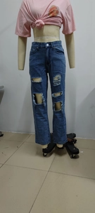 Detail view of high-waist distressed denim jeans with irregular ripped cut-outs