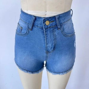 Detail of high waisted light blue denim shorts with distressed fringe hem and gold button