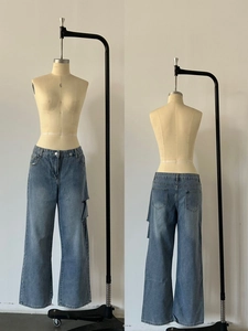 Detail of light blue wide-leg cargo jeans with side pockets and washed denim finish
