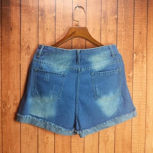 Blaue Jeans-Shorts im Distressed-Look mit Vintage-Waschung und Fransen am Holz-Hintergrund