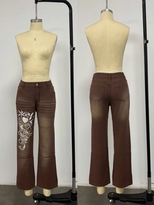 Détail montrant l'effet délavé vintage et l'imprimé graphique cœur sur le pantalon denim