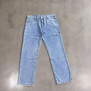Detailed flat lay of light blue relaxed fit denim jeans with washed finish on stone surface
