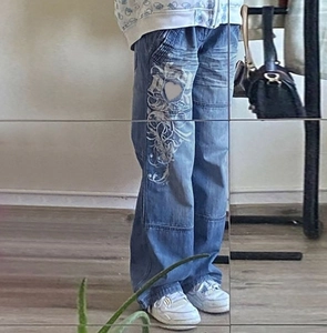 Détail du jean large bleu clair avec imprimé cœur blanc et motifs graphiques gothiques