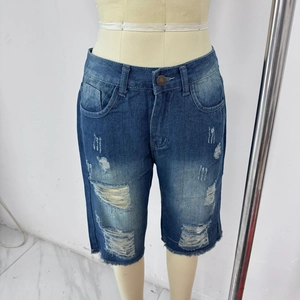 Detailed close-up of blue distressed denim shorts with ripped details and frayed hem