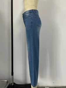 Detail view of blue washed denim texture and side seam on wide-leg jeans with cat-whisker effect