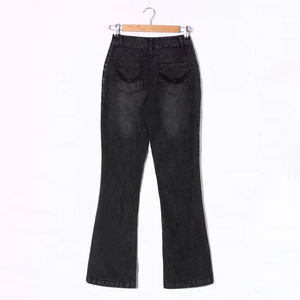 Detail of vintage grey flare jeans featuring black embroidered wing patterns on back pockets