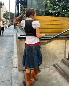 Style urbain avec un gilet en jean noir ajusté et une chemise blanche à manches bouffantes