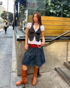 Détail d'un gilet en jean tendance avec boutons en métal et chemise blanche à volants