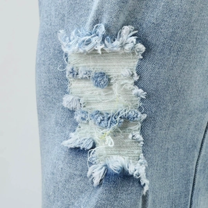 Detailaufnahme der hellblauen Jeans mit modischen Rissen und Fransen im Vintage-Stil