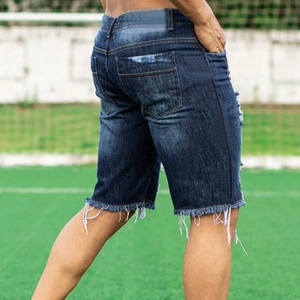 Macro view of blue slim fit denim shorts showing distressed ripped edges and side stripe