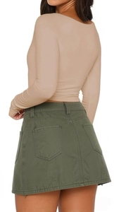 Dettaglio della maglia kaki a maniche lunghe e gonna di jeans verde con tasche posteriori