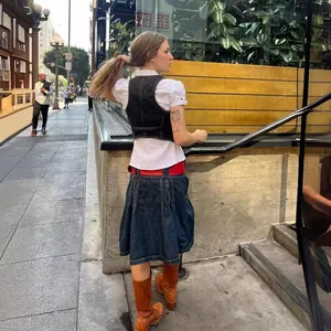 Gilet en jean noir pour femme porté sur une chemise blanche à manches bouffantes