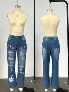 Detail of high waist ripped jeans with floral print patches and distressed denim texture