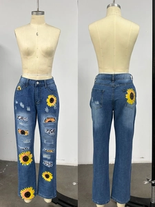 Detail of blue denim jeans with leopard print patches and sunflower embroidery accents