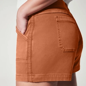 Detailed close-up of terracotta stretch denim shorts featuring back pocket and twin-needle stitching