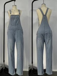 Détails de la salopette en jean bleu clair avec boucles métalliques et poche centrale