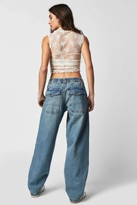 Dettaglio dei jeans a gamba larga con grandi tasche posteriori e crop top in pizzo