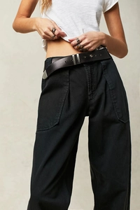 Dettaglio dei pantaloni neri a vita alta a gamba larga con cintura in pelle e fibbia argento