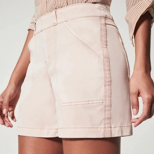 Detail of light pink high-waisted denim shorts with large pockets and side tape accents