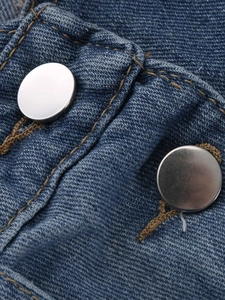 Détail des boutons en métal et coutures brunes sur cette salopette en jean bleu