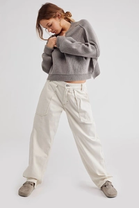 Dettaglio dei pantaloni a gamba larga bianco sporco con tasche cargo e cuciture a contrasto