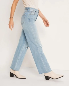 Detail view of high-waist light blue straight-leg jeans with distressed knee holes and frayed hems