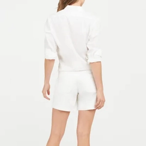 Rear view of minimalist white long-sleeve cotton shirt and matching casual shorts outfit