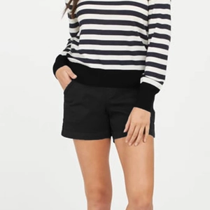 Detail shot of slim fit black denim shorts paired with a striped knit sweater