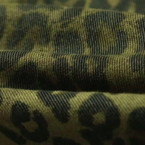 Gros plan du tissu denim imprimé léopard vert armée avec texture de tissage sergé